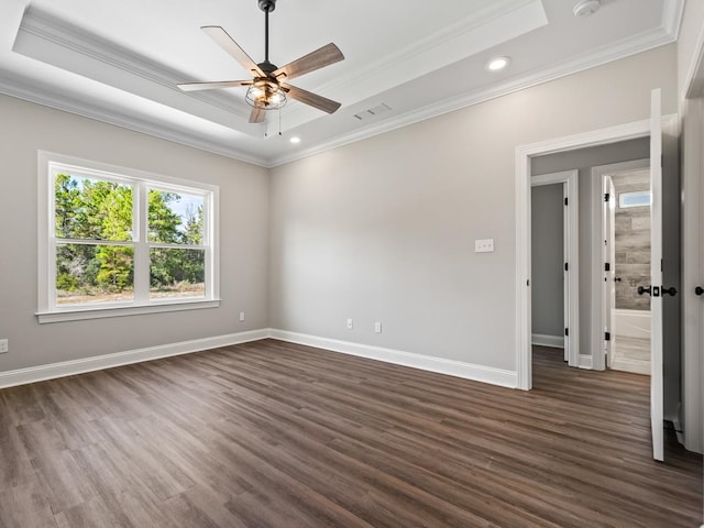 unfurnished room with ceiling fan, a tray ceiling, dark hardwood / wood-style floors, and crown molding