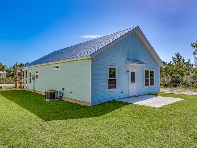 rear view of property with central AC unit, a lawn, and a patio area