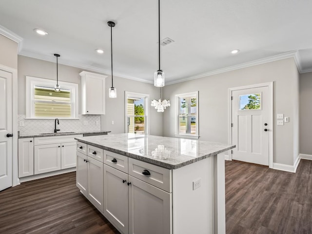 kitchen featuring a kitchen island, white cabinetry, dark hardwood / wood-style floors, light stone countertops, and sink