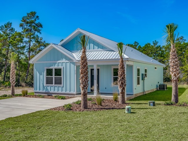 rear view of house with central air condition unit, a porch, and a yard