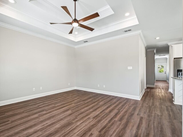 unfurnished room with dark hardwood / wood-style flooring, ceiling fan, a raised ceiling, and crown molding