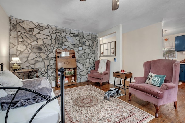 living area with sink, a textured ceiling, wood-type flooring, and ceiling fan