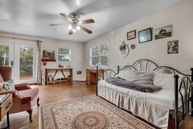 bedroom featuring ceiling fan, hardwood / wood-style floors, and a textured ceiling