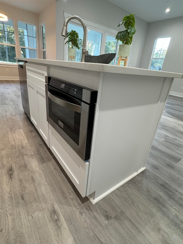 kitchen with plenty of natural light, a center island, white cabinetry, and light hardwood / wood-style flooring