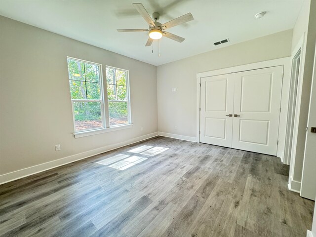 unfurnished bedroom featuring ceiling fan, light hardwood / wood-style floors, and a closet