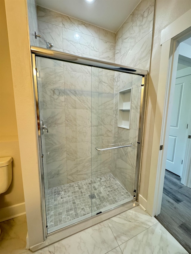 bathroom with wood-type flooring, an enclosed shower, and toilet