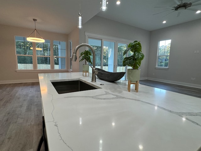 kitchen with light stone countertops, hanging light fixtures, a healthy amount of sunlight, and sink