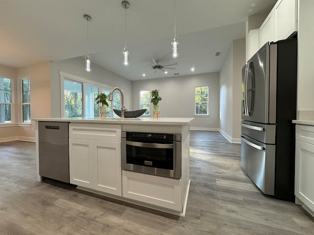 kitchen with white cabinets, light hardwood / wood-style floors, and appliances with stainless steel finishes