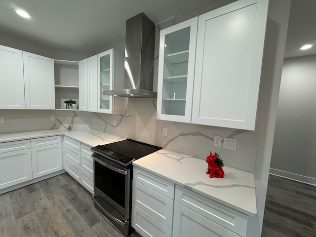 kitchen featuring light stone counters, stainless steel electric stove, wall chimney range hood, hardwood / wood-style floors, and white cabinetry