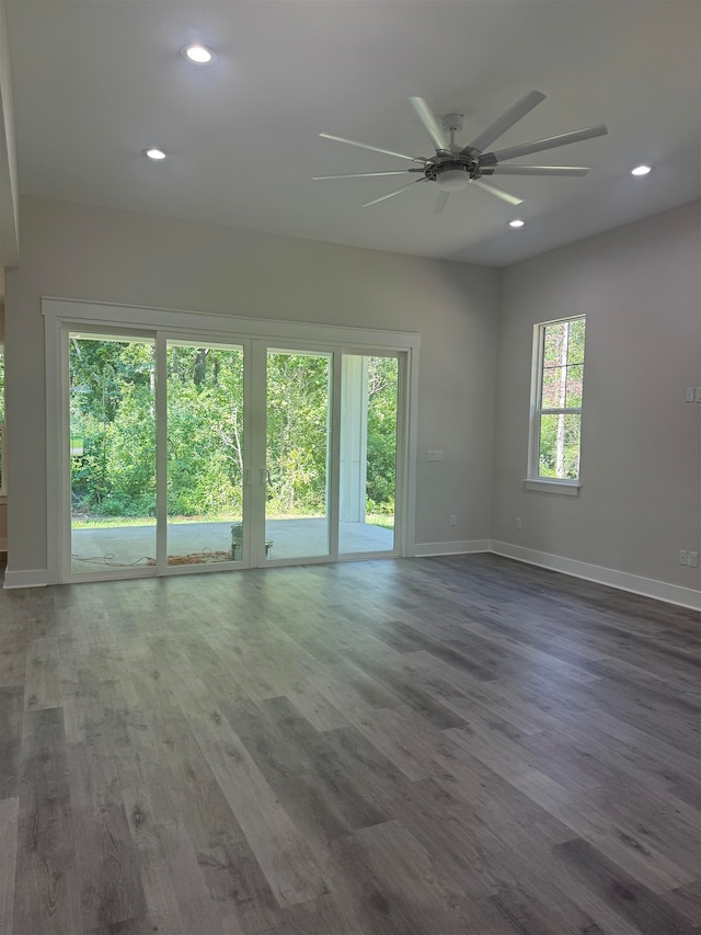 unfurnished room featuring ceiling fan, dark wood-type flooring, and a wealth of natural light