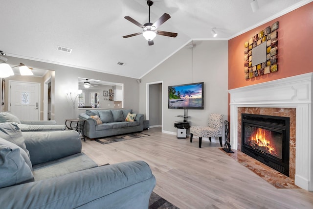 living room featuring crown molding, a premium fireplace, ceiling fan, high vaulted ceiling, and light wood-type flooring