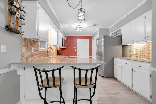 kitchen featuring stainless steel appliances, white cabinetry, a kitchen breakfast bar, and kitchen peninsula