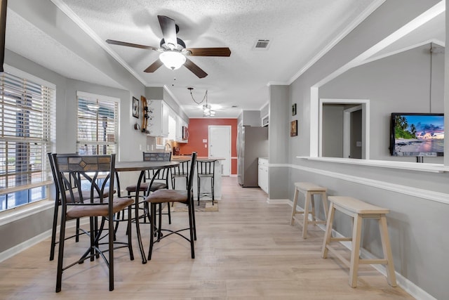 dining area with crown molding, light hardwood / wood-style flooring, and a textured ceiling