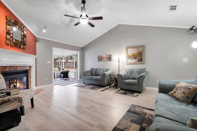 living room with lofted ceiling, crown molding, light wood-type flooring, ceiling fan, and a premium fireplace