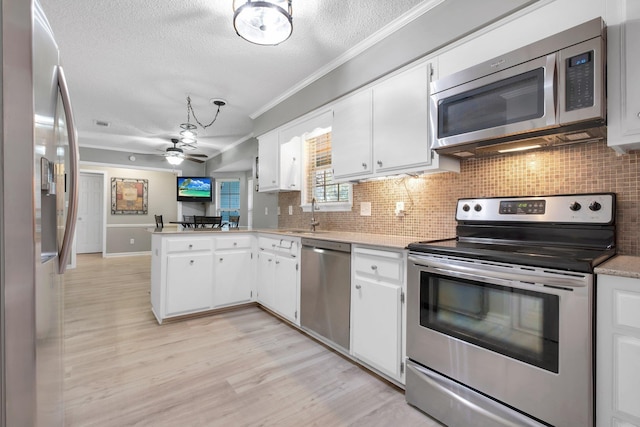 kitchen featuring crown molding, backsplash, stainless steel appliances, white cabinets, and kitchen peninsula