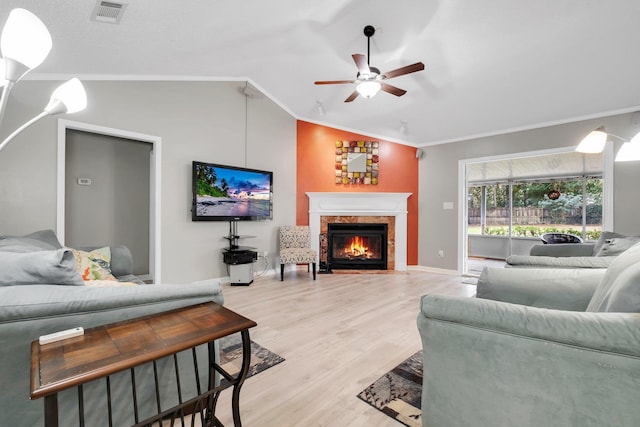 living room featuring ceiling fan, ornamental molding, light hardwood / wood-style floors, and vaulted ceiling