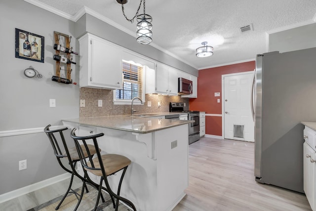 kitchen with sink, white cabinetry, hanging light fixtures, kitchen peninsula, and stainless steel appliances