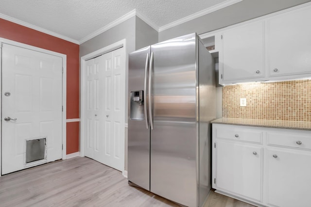 kitchen featuring white cabinets, crown molding, stainless steel fridge, and light hardwood / wood-style flooring