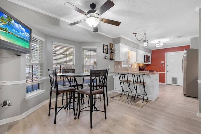 dining area with ornamental molding, sink, light hardwood / wood-style floors, and a textured ceiling