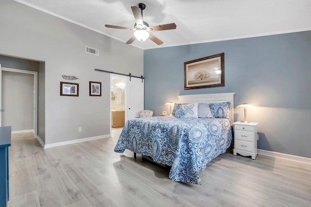 bedroom with lofted ceiling, light wood-type flooring, ornamental molding, ceiling fan, and a barn door