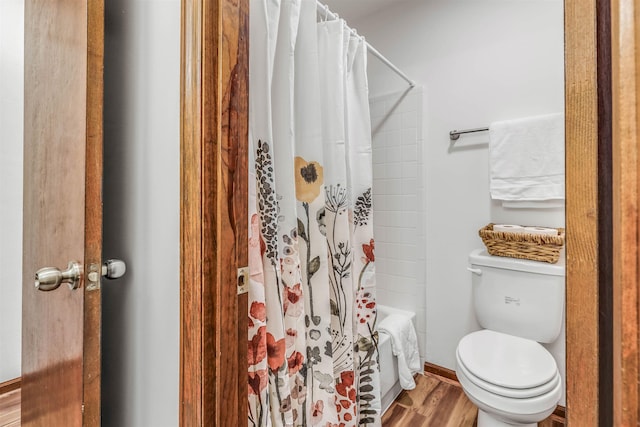 bathroom featuring shower / bathtub combination with curtain, hardwood / wood-style floors, and toilet