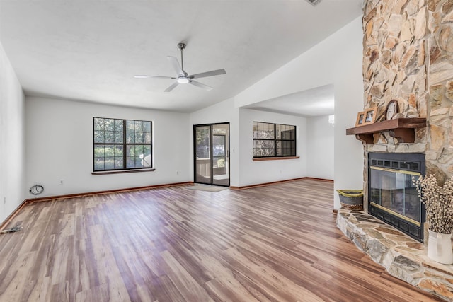 unfurnished living room featuring lofted ceiling, ceiling fan, heating unit, light hardwood / wood-style floors, and a stone fireplace