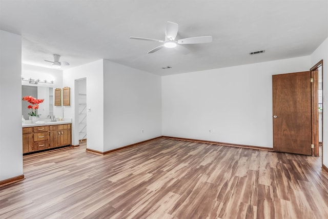 unfurnished bedroom featuring ceiling fan, ensuite bathroom, sink, and light hardwood / wood-style floors