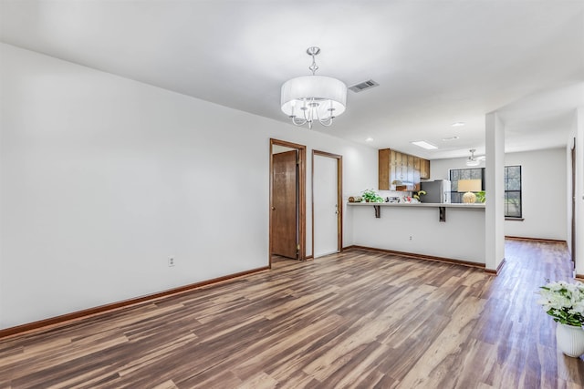 unfurnished living room featuring hardwood / wood-style flooring and a chandelier