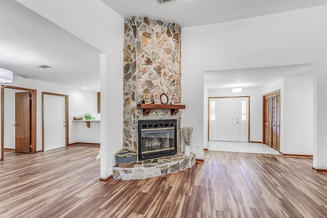 living room with a stone fireplace and light wood-type flooring