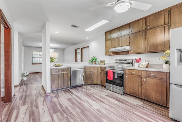 kitchen with stainless steel appliances, ceiling fan, light wood-type flooring, and kitchen peninsula