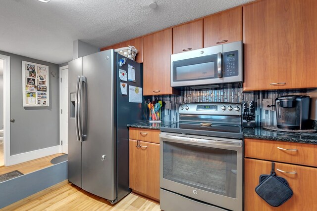 300 S Duval St # 508, Tallahassee, FL 32301 - kitchen featuring stainless steel appliances, light wood-type flooring, backsplash, brown cabinets, and a textured ceiling