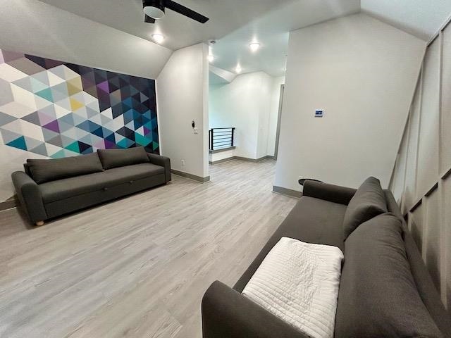 living room featuring ceiling fan, light hardwood / wood-style flooring, and lofted ceiling