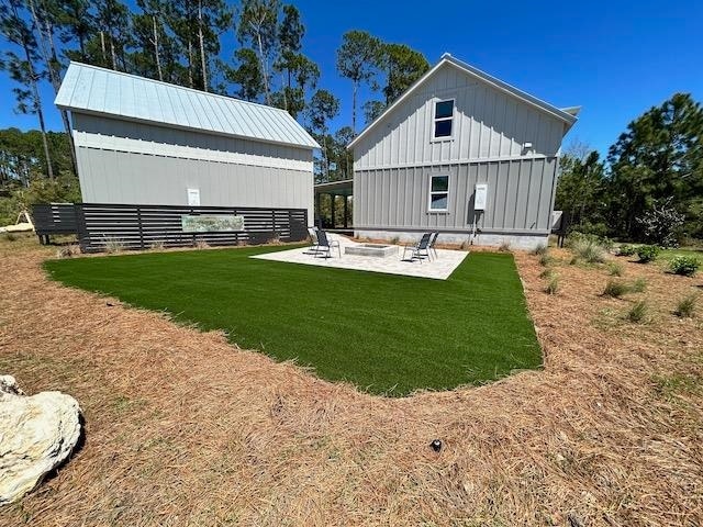 back of property featuring a yard, a patio, and an outdoor fire pit