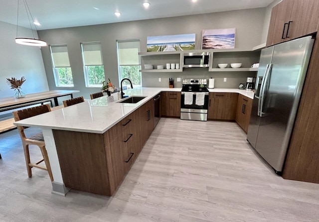 kitchen featuring hanging light fixtures, sink, a breakfast bar area, light hardwood / wood-style floors, and stainless steel appliances