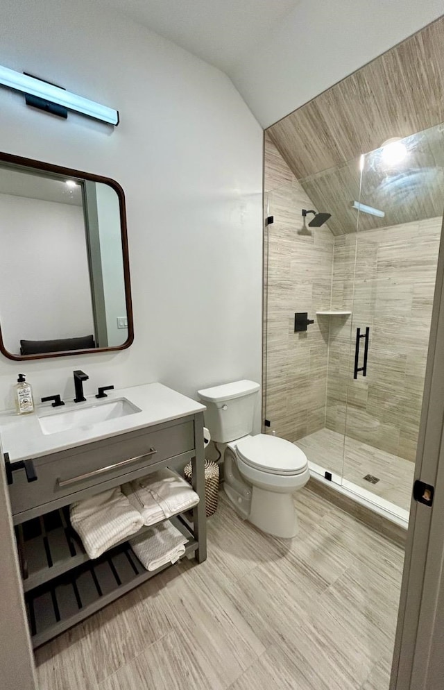 bathroom featuring vanity, toilet, a shower with shower door, and vaulted ceiling