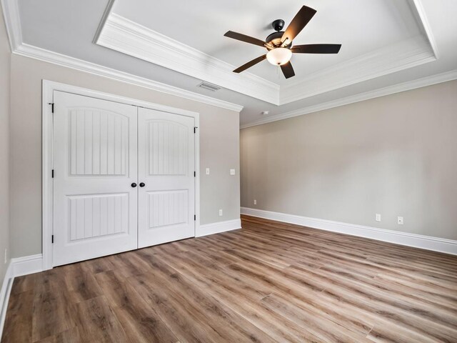 45 Sioux Trl, Crawfordville, FL 32327 - unfurnished bedroom featuring a tray ceiling, wood finished floors, a closet, baseboards, and ornamental molding