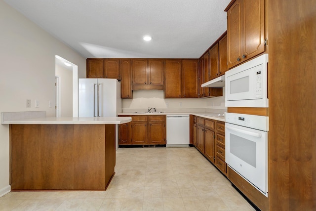 3024 S Shamrock, Tallahassee, FL 32309 - kitchen featuring a sink, white appliances, light countertops, brown cabinetry, and under cabinet range hood