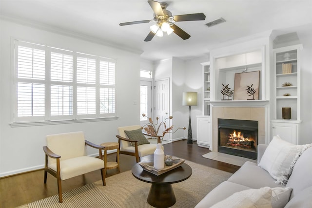 living room with visible vents, a fireplace, crown molding, and wood finished floors