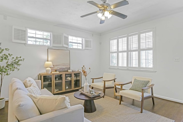 living area featuring crown molding, wood finished floors, baseboards, and ceiling fan