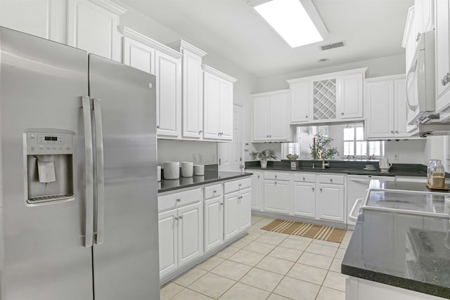 kitchen featuring light tile patterned floors, white microwave, white cabinets, and stainless steel fridge with ice dispenser