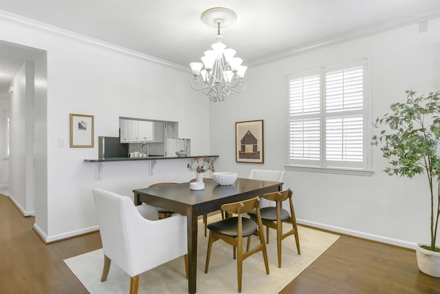 dining space featuring a chandelier, crown molding, baseboards, and wood finished floors