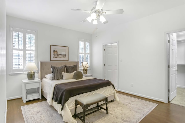 bedroom with a spacious closet, baseboards, and wood finished floors