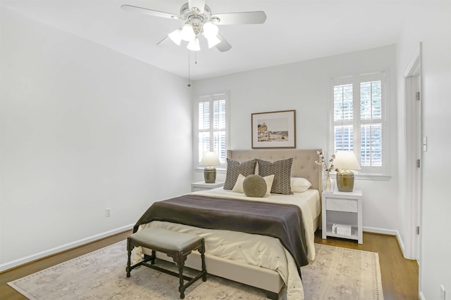 bedroom with multiple windows, a ceiling fan, baseboards, and wood finished floors