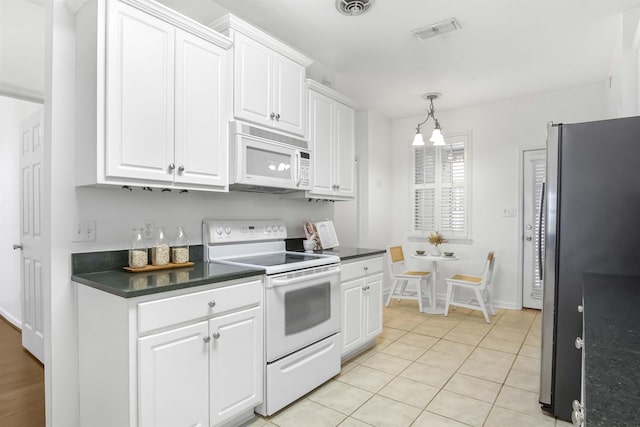 kitchen featuring dark countertops, a chandelier, light tile patterned floors, white appliances, and white cabinetry