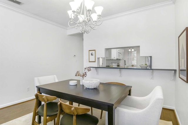 dining room with wood finished floors, baseboards, a chandelier, and ornamental molding