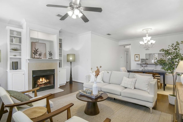 living room featuring visible vents, dark wood-style floors, crown molding, and ceiling fan with notable chandelier