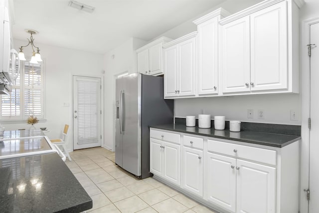 kitchen with visible vents, dark countertops, white cabinets, and stainless steel fridge with ice dispenser