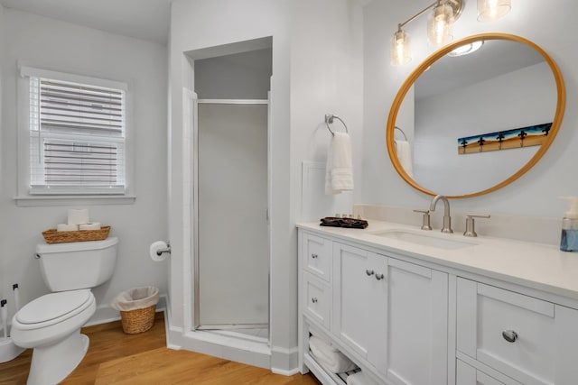 bathroom featuring wood-type flooring, vanity, a shower with door, and toilet