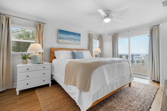 bedroom featuring access to exterior, light wood-type flooring, multiple windows, and ceiling fan