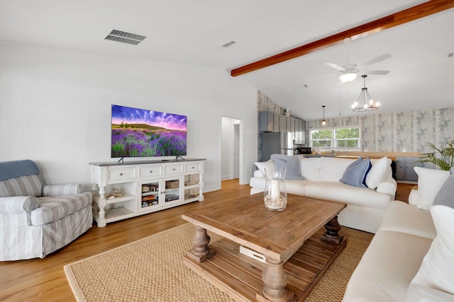 living room with ceiling fan with notable chandelier, light hardwood / wood-style floors, and vaulted ceiling with beams